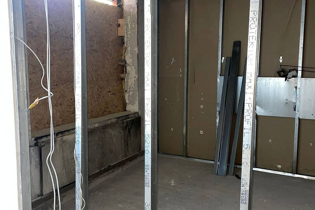 Metallständerwerk für neue Wände im entkernten Brandzimmer, im Hintergrund das verschlossene Fenster