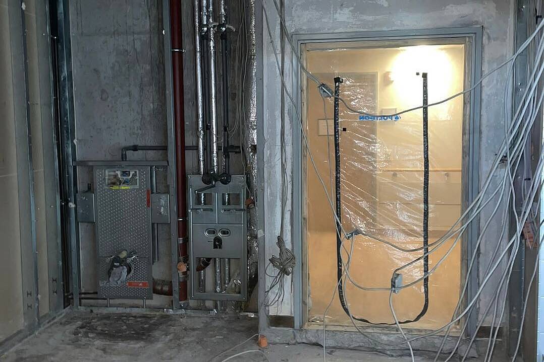 Rohbau mit Vorwandelementen für WC und Waschbecken, freiliegenden Leitungen, Lüftungsrohr und einer mit Folie abgeklebten Tür